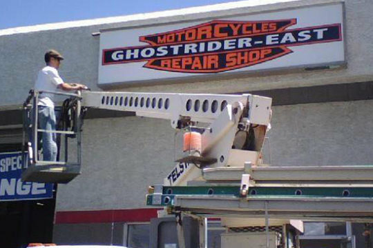 A man installing a repair shop sign.