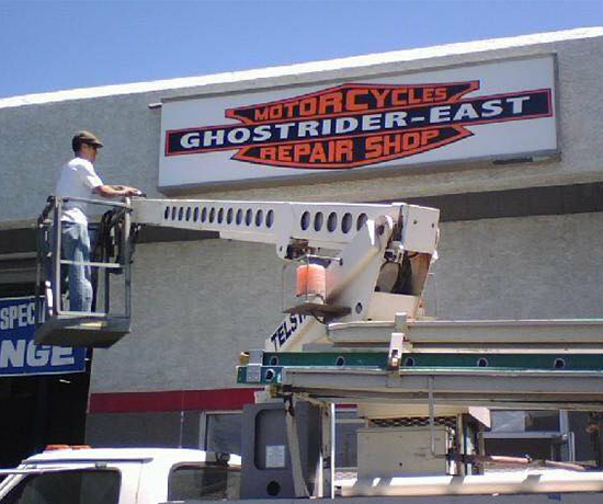 A man installing a repair shop sign.